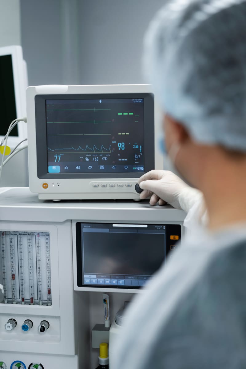 Profissional de saúde operando um monitor multiparamétrico em ambiente hospitalar